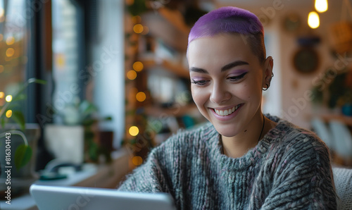 Happy candid mixed race lesbian woman with purple buzzcut hairstyle playing on smart tablet device. Copy space