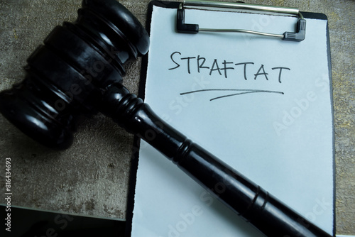 Concept of Learning language - German. Straftat it means crime written on paperwork. German language isolated on Wooden Table.