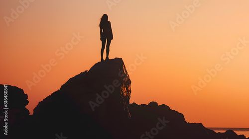 Woman or man standing on rock looking straight Nature and beauty concept Orange sundown Girl silhouette at sunset : Generative AI