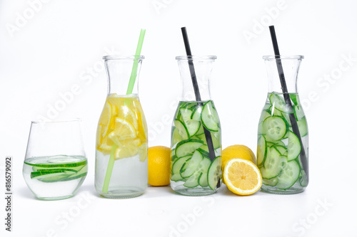 Woda smakowa, woda z plastrami cytryny i woda z ogórkiem pokrojonymi w plastry w szklanych szklankach ze słomką na bialym tle, zdrowy nawadniający napój 