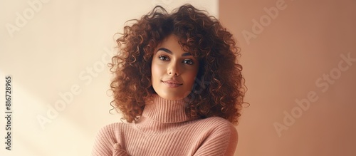 A stunning Arab girl with curly hair wearing a cozy knitted sweater effortlessly grabs attention as she directs her gaze towards the side showcasing an advertisement in the copyspace image