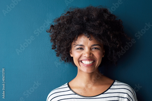 Black woman, portrait and smile with funny, glow and confident on blue studio background. Girl, model and face with afro laughing for joke, comic and happiness or positive with natural beauty