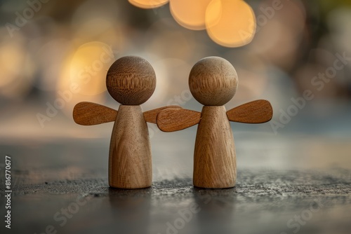 Closeup of two wooden angel figurines side by side with outstretched arms, on a dark background