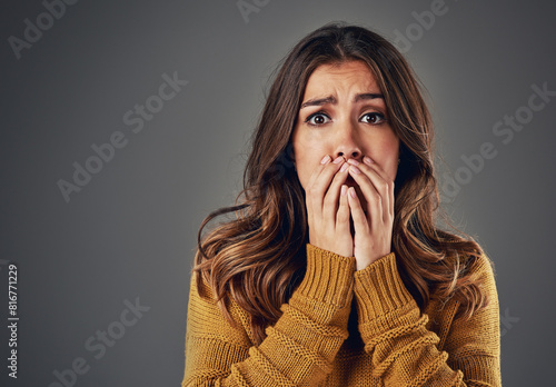 Portrait, scared and woman with fear, afraid and anxiety with secret news on grey studio background. Face, person and model with surprise, shocked and cover mouth with emotions and emoji of gossip