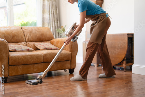 woman with vacuum cleaner cleaning floor at home