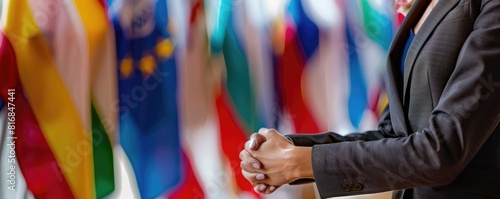 Two diplomats shaking hands with various flags in the background. 