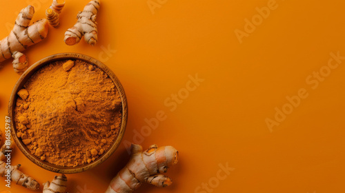 Top view of turmeric powder in a bowl with scattered fresh curcuma roots on a bold orange backdrop with copy space