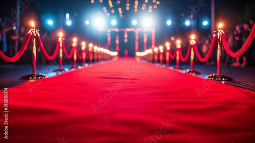A glamorous red carpet event featuring a brightly lit pathway lined with red ropes and stanchions, flanked by spotlights and an elegant ambiance, perfect for premieres or award ceremonies.
