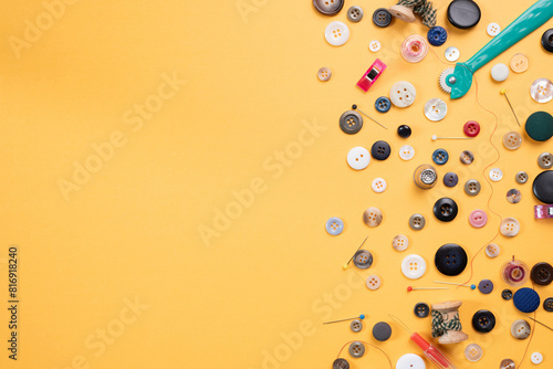 Sewing, needlework supplies, craft, hobby. Buttons, bobbins, thread, pins, yellow background