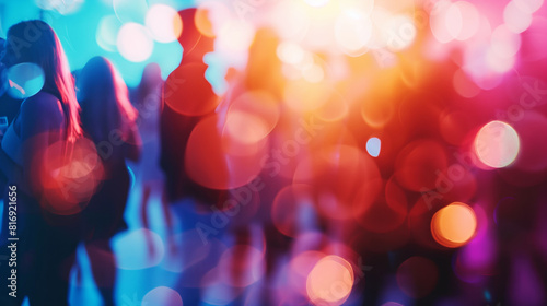 Blurred silhouettes of people mingling at a festive event with vibrant, colorful bokeh lights creating a lively atmosphere.
