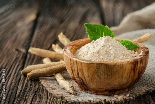 Organic ashwagandha powder in a wooden bowl with fresh roots and green leaves on a rustic wooden background