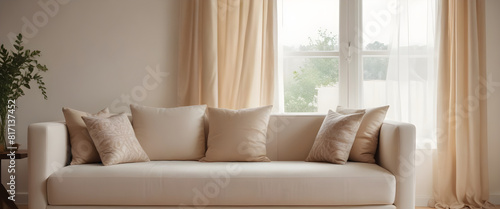 Cozy and stylish living room featuring a beige couch, neutral-toned pillows, large windows, and sheer curtains in a modern home