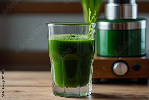 Concentrated wheatgrass shot in a transparent glass with lush green blades and juicer. 