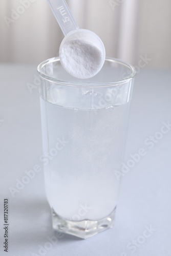 Adding baking soda into glass of water at white table