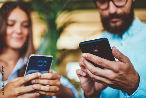 Selective focus on male and female hands holding smartphone devices and messaging with friends ignoring live communication, man and woman using digital gadgets for updating profiles in social networks