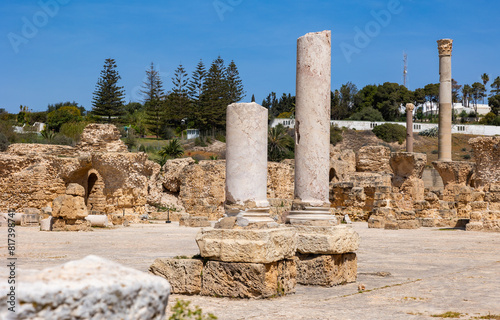 View of sun-drenched ruins of Roman Baths complex of Antoninus in ancient Phoenician town of Carthage with remnants of marble Corinthian columns and stone structures, Tunisia