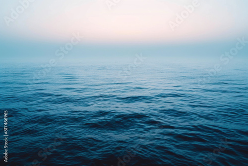 Endless ocean under a hazy sky at dawn, capturing the peaceful, misty atmosphere of the sea blending into the horizon.