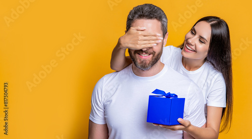 Loving woman giving present for Valentines day. Gift box to surprised man. Boyfriend receiving present from girlfriend. Valentines day couple. Couple in love. Mans day gift. Copy space