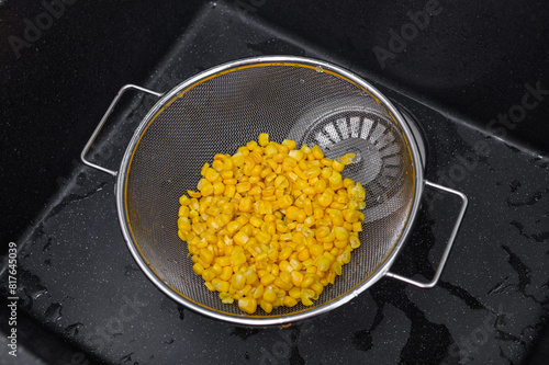 Odsączać kukurydzę konserwową z zalewy na sitku w zlewie