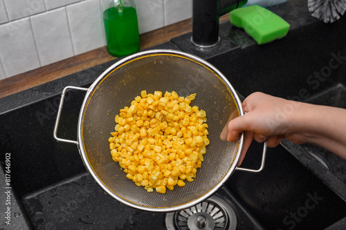 Żółta słodka kukurydza z puszki, chrupiące ziarna na sitku kuchennym z bliska 