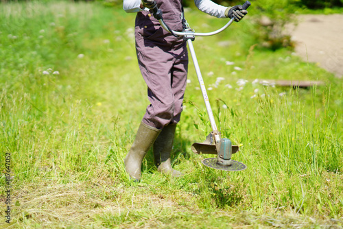 電動草刈り機で草刈りをする女性