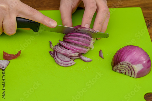 Kroić czerwona cebulę w piórka na desce do krojenia 