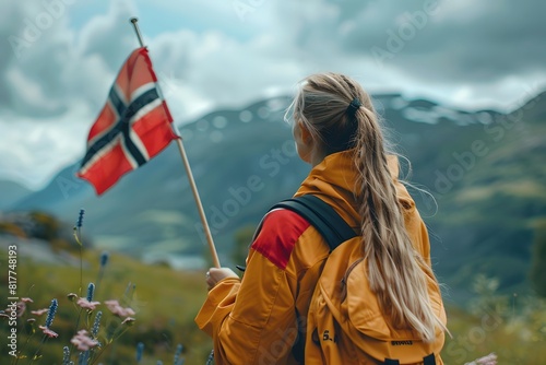 Blond woman with backpack looking at norwegian flag on mountain