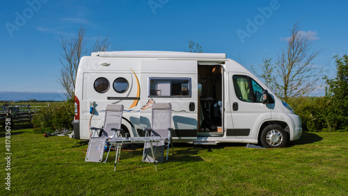 A modern RV is peacefully parked on a lush green field in Texel, Netherlands, surrounded by the beauty of nature under a clear blue sky.