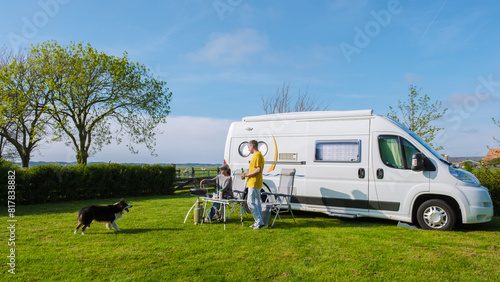 A man and his faithful dog stand next to an RV in a picturesque grassy field in Texel Netherlands, soaking in the serenity of their surroundings. a couple at a camping farm