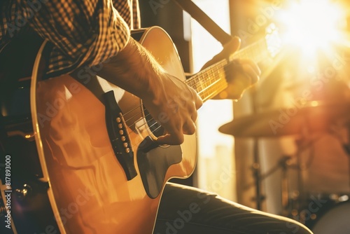 Close-up of a musician playing an acoustic guitar with sunlight streaming through the window, creating a warm and vibrant atmosphere.