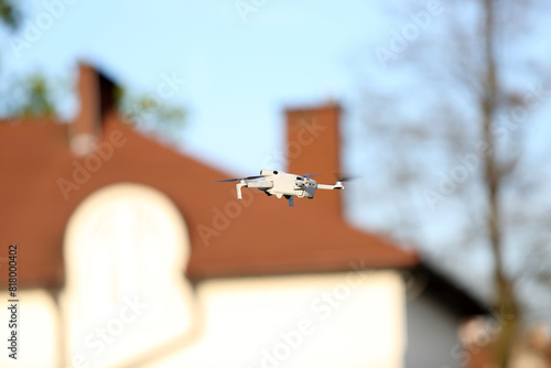 Dron w powietrzu, w locie na tle dachu budynku.