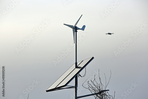 Panel słoneczny, turbina wiatrowa na latarni ulicznej, dron w powietrzu.