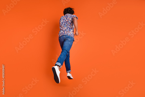 Full length photo of handsome young man running turn around back dressed stylish colorful garment isolated on orange color background