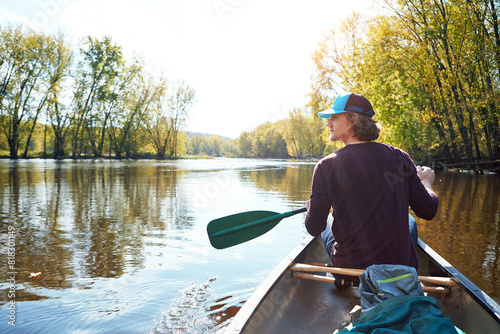 Man, canoeing and lake rowing in nature for morning adventure or exercise, exploring or island. Male person, back and Colorado traveling for outdoor hobby with boat at camp site, forest or nature