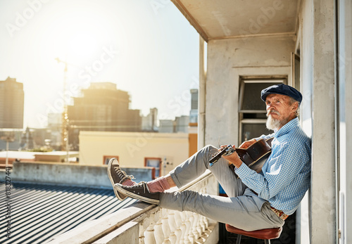 Artist, senior and man with acoustic guitar for playing with retired musician on balcony in town for memories. Elderly, creative and proud of accomplishments with blues or folk song in urban Italy.