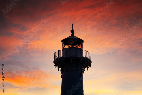 Vibrant orange crimson sunset with silhouette of lighthouse head below