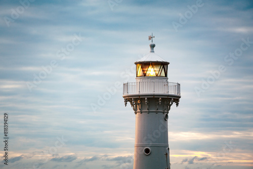 Head of a light house shining in a blue pastel colored sky
