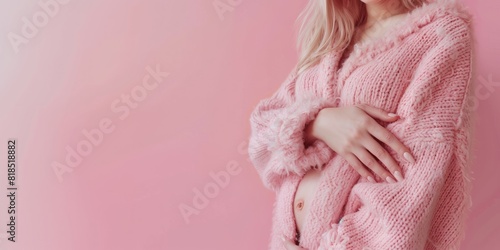 A pregnant woman tenderly hugs her belly on a pink background. The concept of preparing women for pregnancy, childbirth, motherhood, copy space