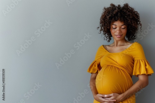 Pregnant African American woman tenderly hugging her belly on a gray background. The concept of preparing women for pregnancy, childbirth, motherhood, copy space 