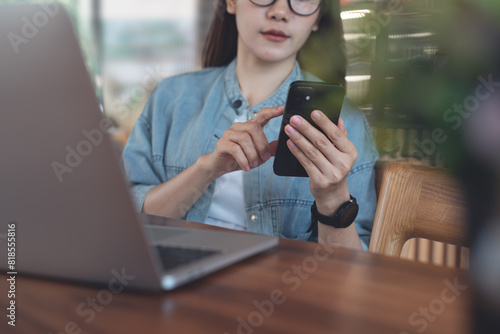 Casual business woman working at coffee shop, using mobile phone with laptop computer on table. Asian freelancer online working from cafe, connecting the internet, free wifi, portable office concept