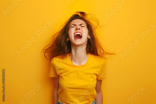 Angry woman yelling in studio over yellow background