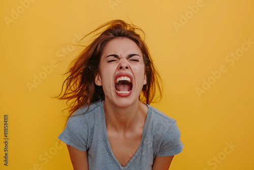 Angry woman yelling in studio over yellow background