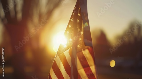 A close-up of a weathered American flag waving proudly, backlit by a warm, glowing sunset, symbolizing freedom and resilience