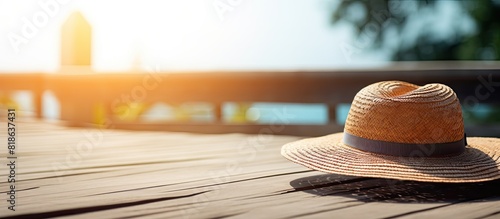 The wooden deck holds a sunlit wet straw hat with a copy space image It s perfect for beachside restaurants or outdoor gatherings