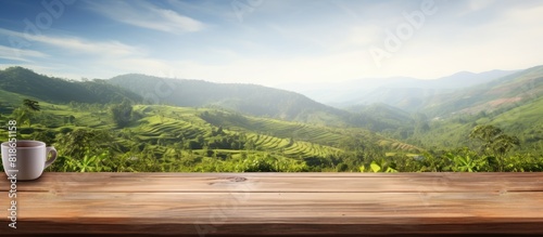 Copy space image of an empty wooden table overlooking a picturesque mountain or a wooden desk surrounded by a serene tea plantation with a blurred bokeh background Add your own text