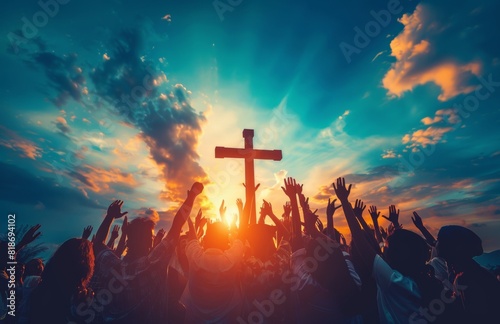 A group of people raising their hands in worship, with the silhouette of an cross above them against a sky background. The scene is illuminated by sunlight rays and conveys unity