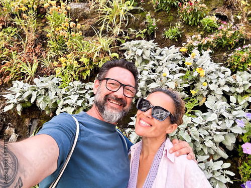 Happy couple middle age of tourist taking selfie picture together with leaves wall in background exploring city and destination. Traveler have fun in relationship. People and lifestyle with love