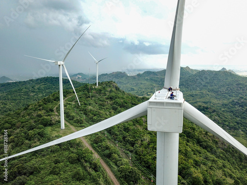 Wind turbine technicians work on the nacelle of a turbine in the wind farm area.