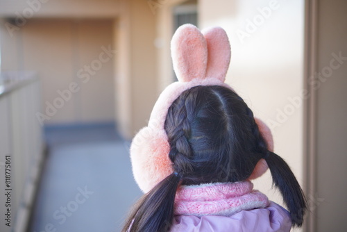 うさぎの耳当てを小学生の女の子が身につけている後ろ姿。