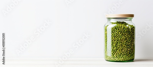 There is a jar filled with green buckwheat situated on a white table leaving space available for text. Copyspace image